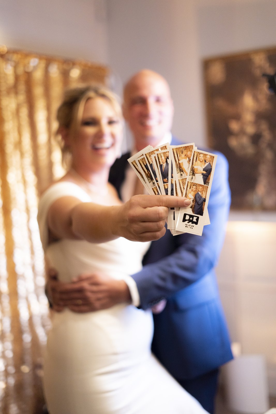 Bride holding up a freshly printed photo booth strip from her wedding reception